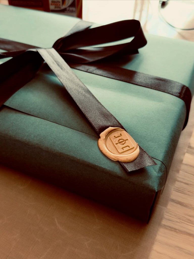 A green TrikotTrader mystery box finished with ribbon and a wax seal